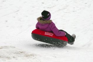 A young festival goer catches air snowtubing.